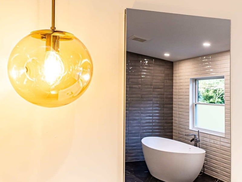 Pendant light in bathroom remodel in Boston with freestanding tub in mirror by Honorato Company